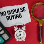 No Impulse Buying text with alarm clock, magnifying glass anc calculator on red background
